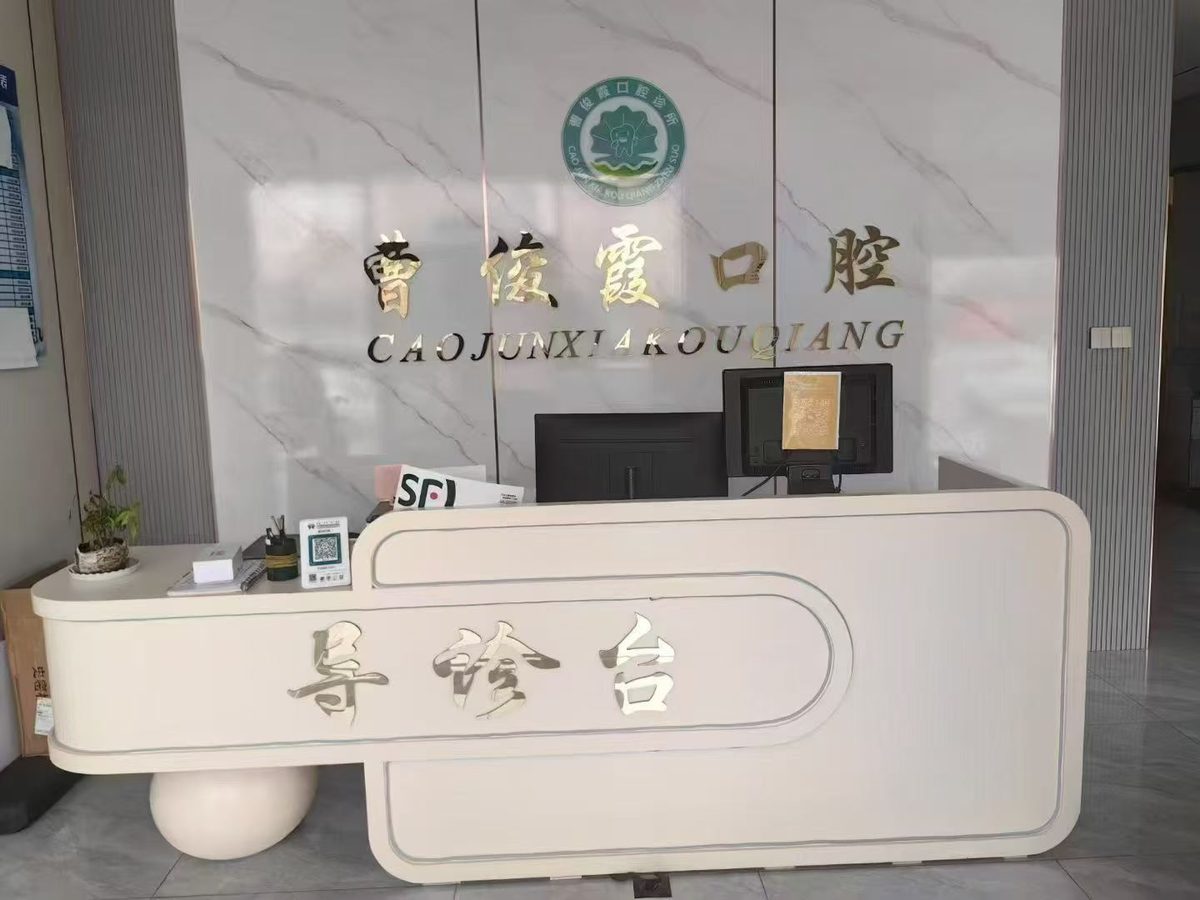 曹俊霞口腔导诊台实拍，前台背景墙为品牌金色立体字与圆形标识