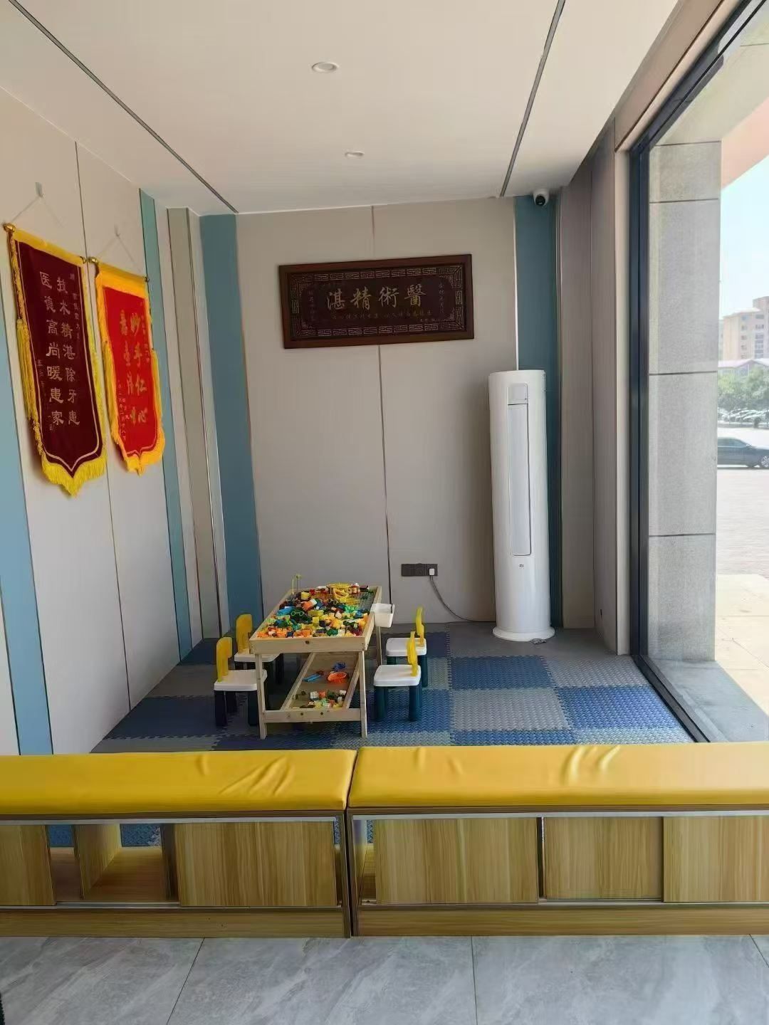 曹俊霞口腔儿童等候区实拍，木质积木桌与黄色软包长凳